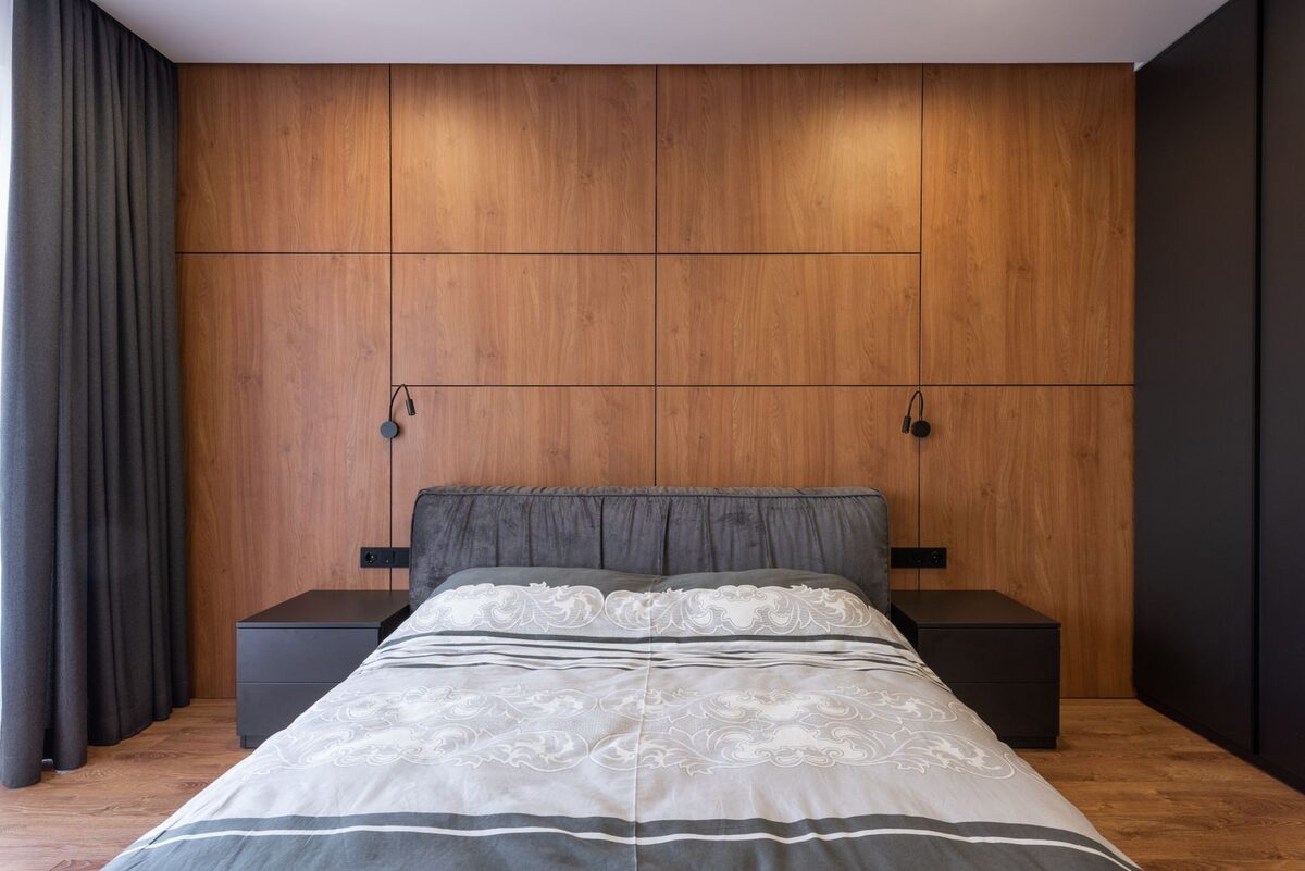 Wood-panelled bungalow bedroom with a low double bed and soft natural light