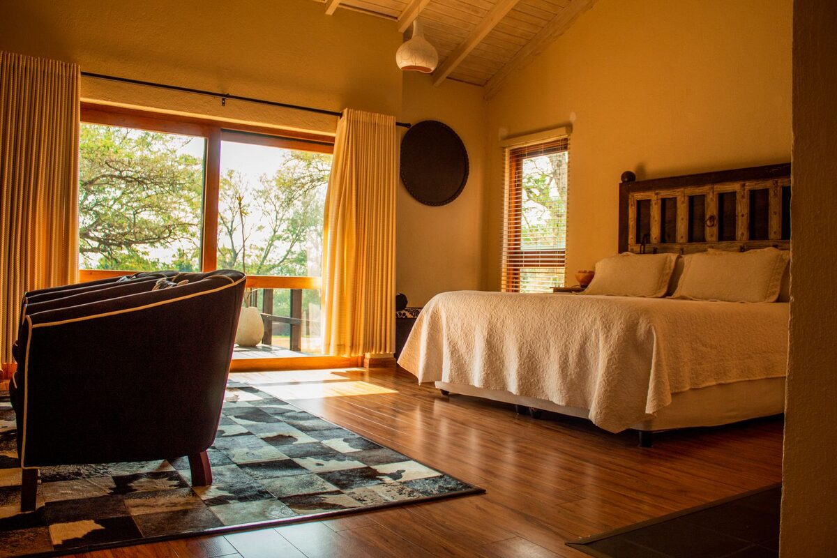Warm cabin-style bedroom opening onto a green garden view
